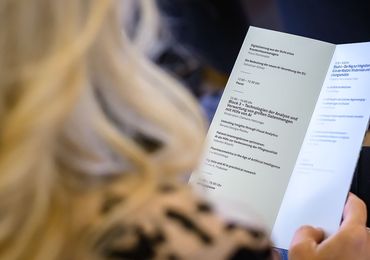 Woman in the audience holding a program — Picture: MedUni Wien / Marko Kovic